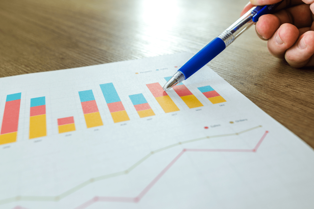 A person holding a pen on a paper with graphs on it.