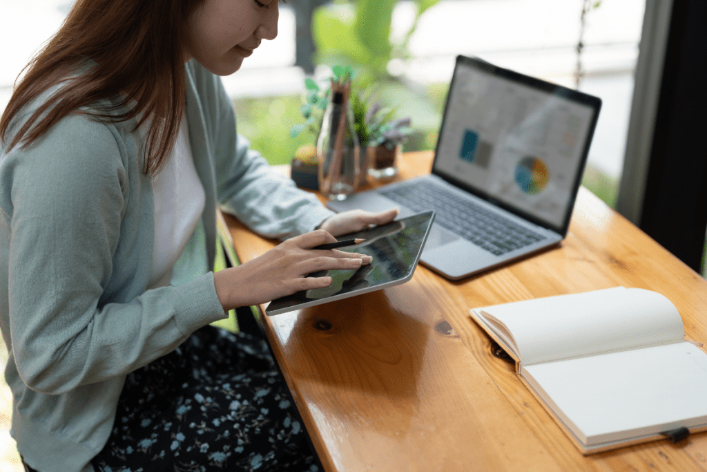 A woman sitting at a table with a laptop and tablet.