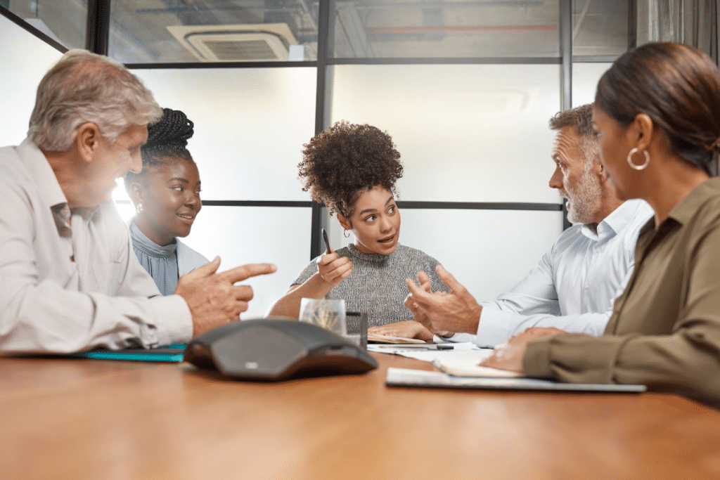 A group of people sitting around a table in a meeting.