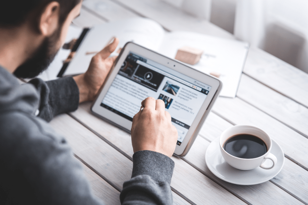 A man is using a tablet computer with a cup of coffee.