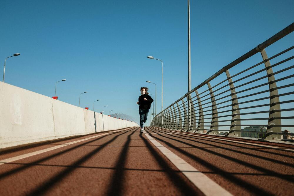 Child running on a bridge with a clear blue sky background