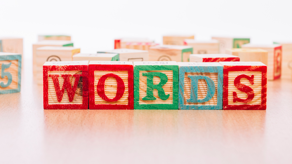 Colorful wooden blocks spelling the word 'WORDS' on a light wooden surface.