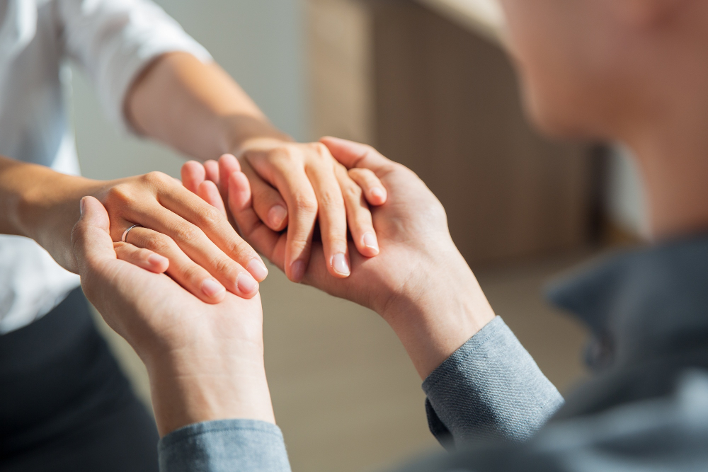 Two people gently holding hands, conveying support and connection.